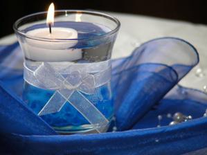 Dekorace - svíčka s vodou (budou v ní kamínky a květ orchideje) a pouze s mašličkou. Pro upozornění, pokud se dávají klasické čajové svíčky, tak se objeví ve skleničky zrezlé fleky, proto je potřeba opravdu koupit svíčky plovoucí.