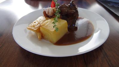 Grilovaný hovězí steak z naší vyzrálé květové špičky Black Angus, podávaný s kachními foie gras, glazovanými liškami a česnekovým konfitem, burgundská omáčka, pečené bramborové fondány