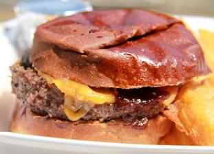 A Raďův oběd -Burger s prorostlou americkou slaninou, sýrem čedar, barbecue omáčkou a cibulovými kroužky.