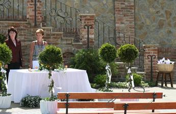 venkovní výzdoba a paní oddávající s matrikářkou. vlevo košíček s kornouty na rýži a okvětní plátky