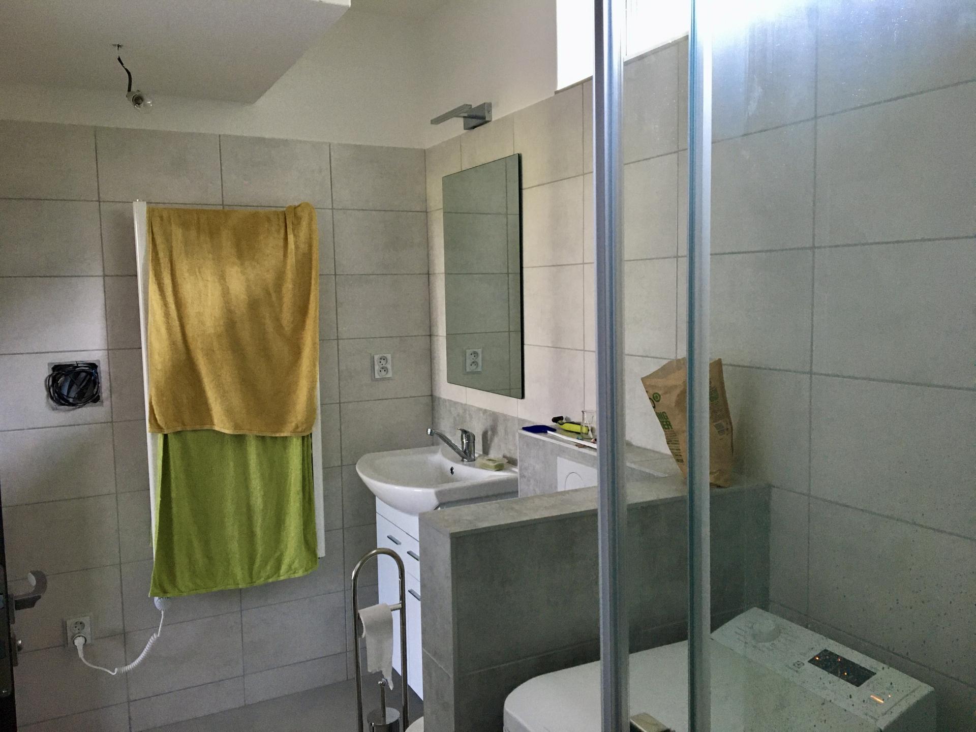 Tohle bude jednou náš dům (stále to vypadá, že pasivní) - Druhá koupelna - pohled ze sprchového koutu ke dveřím a topnému žebříku (neboli sušáku na ručníky, topení je v podlaze)