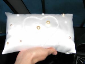 Tak to je můj vlastnoručně vyrobený polštářek pod prstýnky. Fotka se sice moc nevyvedla, ale představu si snad uděláte. Je celej bílej saténovej, uprostřed je vyšitý obrys srdce z perliček a uvnitř jsou dvě velké perly na prstýnky. Okolo jsou vyšité